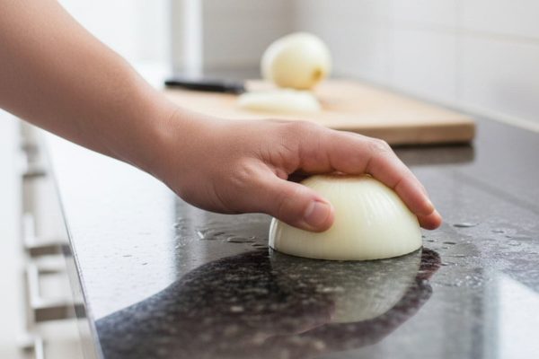 wrijft het aanrechtblad in met ui